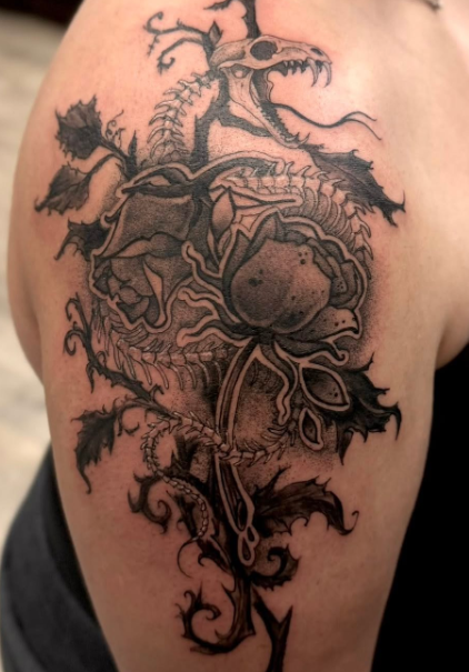 Blackwork shoulder tattoo of a skeletal serpent coiled through roses and thorny vines