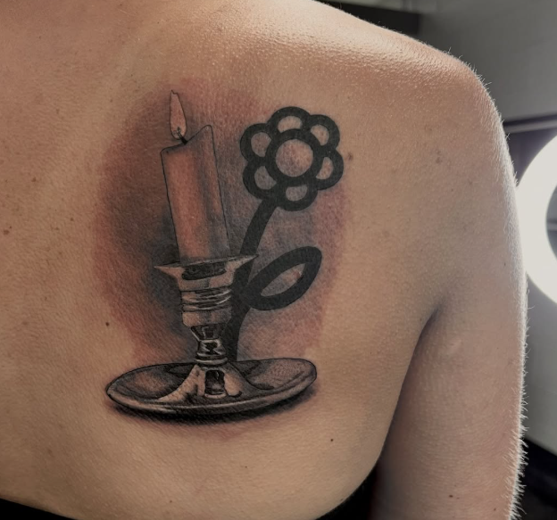 Black and grey shoulder tattoo of a candlestick with a flower