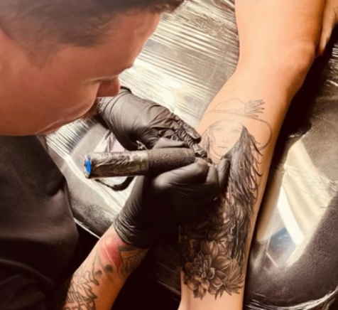 Alen Heric tattooing a black and grey portrait on a client's forearm