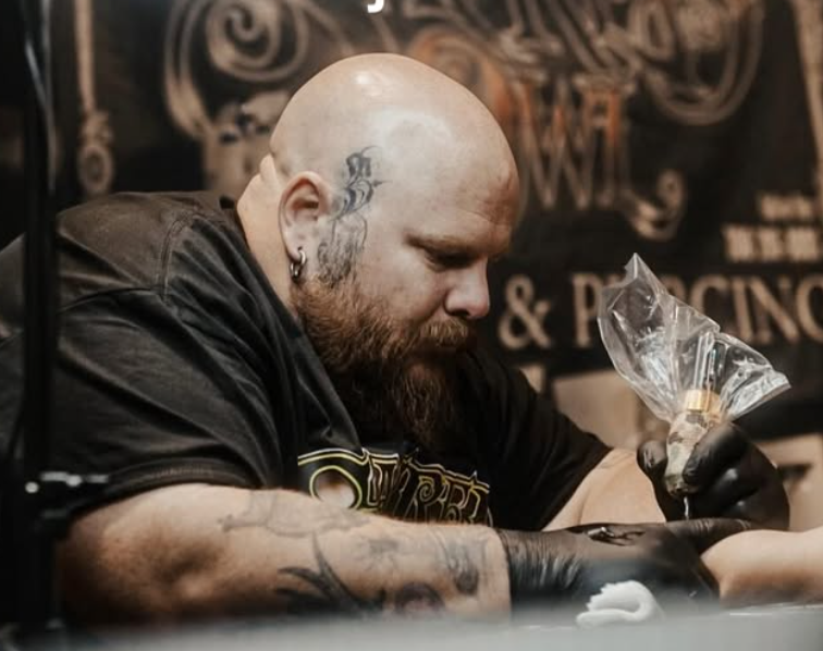 Ben Jones tattooing a client's arm at a convention